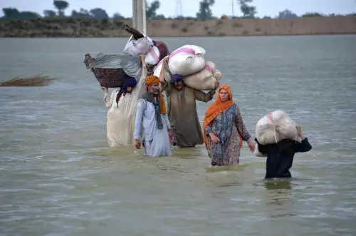 A family wades through floodwaters carrying their luggage