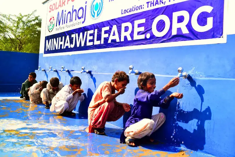 Minhaj Welfare Foundation solar-powered water well in Thar, Pakistan, with children using clean water, supported by Sindh Development Organization (SDO) NGO