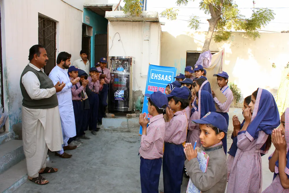 School children in blue uniforms using an electric stainless steel water cooler installed through the Ehsaas Water for Life project in Sindh, Pakistan