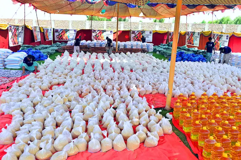 Sindh Development Organization (SDO) food distribution event with volunteers organizing flour and oil bags for underprivileged communities in Pakistan