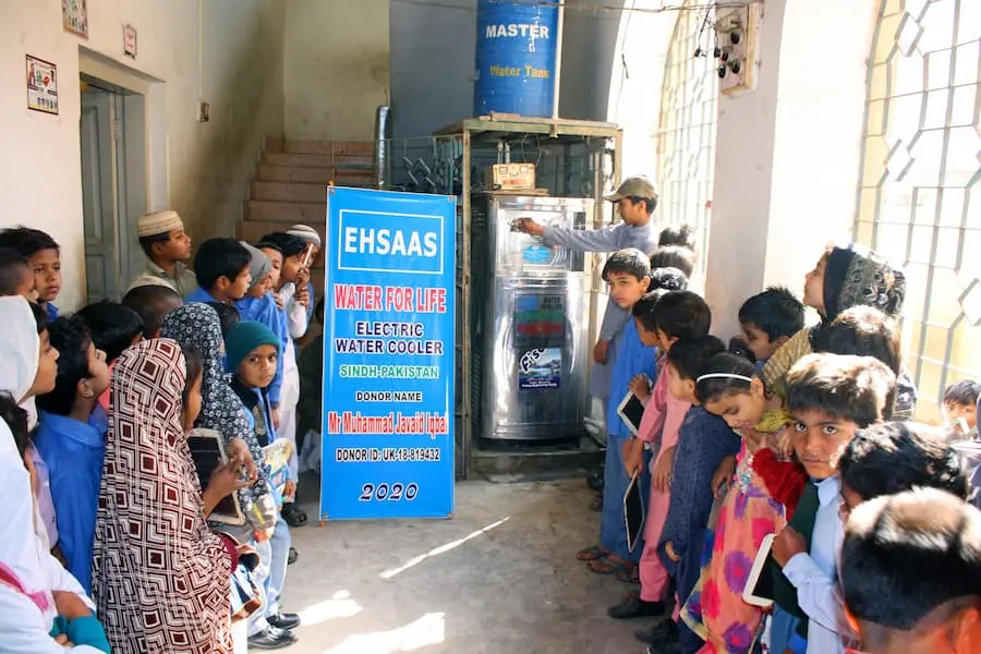 “Group of school children filling water from an electric stainless steel water cooler inside school premises — Water for Life initiative by SDO