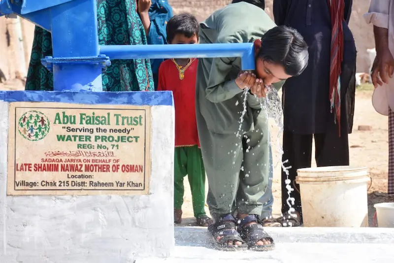Abu Faisal Trust water project in Chak 215, Rahim Yar Khan, Pakistan, providing clean water to a child, supported by Late Shamim Nawaz on behalf of Osman