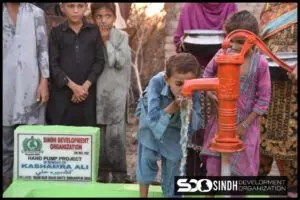 A boy drinking from a small water pump