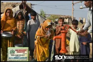 A girl drinking from a small water pump by SDO